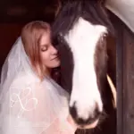 Eine Frau schmust liebevoll im Hochzeitskleid mit Ihrem Pferd
