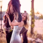 Junge Frau posiert im Wald in Herzogenaurach neben Ihrem Pferd, dass mit eimem Kranz aus Blumen geschmückt ist