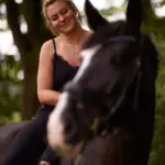 Junge Frau beim Pferdefotoshooting leger auf ihrer Stute